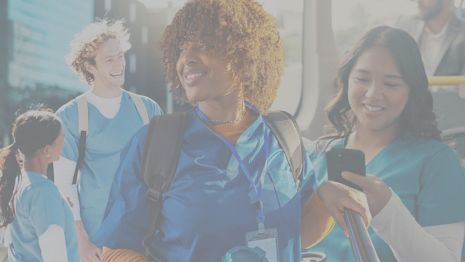 Healthcare travelers in scrubs smiling together on a city bus